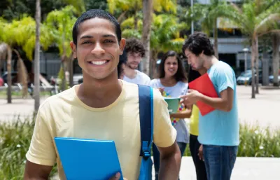 Happy young black man with friends behind him. Benefit of trade school scholarships and grants in supporting young people