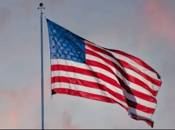 An American flag blowing in the wind with a blue sky in the background.