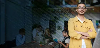 Man standing in front of coding screen with other students in background