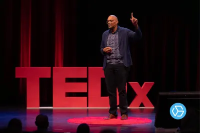 Ted Talk speaker with hand raised to make a point