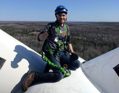 Charlie Tran, wind turbine technician ambassador, gives the thumbs-up on top of a wind turbine