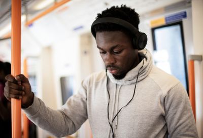 Man on train listens to construction podcast on headphones