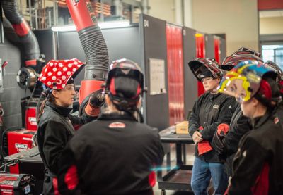 A group of women welders at Lincoln Electric discuss a task. 