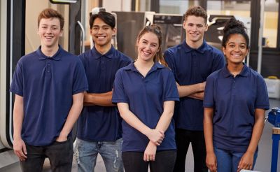 Young apprentices in blue shirts smile for the camera