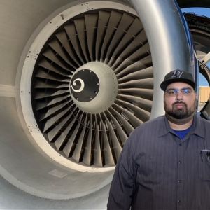 Aircraft mechanic Lorenzo Carlos Perez stands in front of an airplane engine