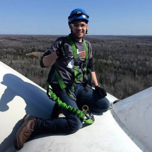 Charlie Tran, wind turbine technician, gives the thumbs-up on top of a wind turbine