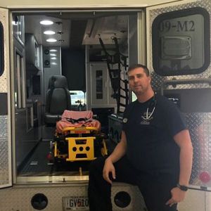 Paramedic Ryan Hollingsworth stands in front of the open back doors of an ambulance