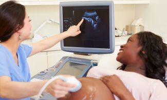 A diagnostic medical sonographer shows a pregnant woman an ultrasound of her baby