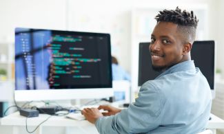 A software developer sits at a computer and writes code
