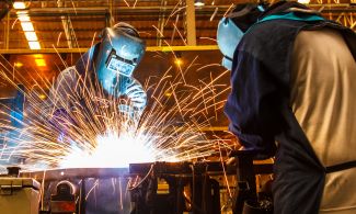 Two welders cut metal in an automotive factory