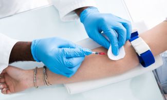 Phlebotomist inserts a needle to take a blood sample