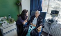 A social services assistant checks on an elderly client in a medical setting