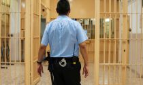 Correctional officer walks through prison aisle