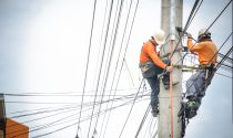 Electrical linemen work on a power line pole
