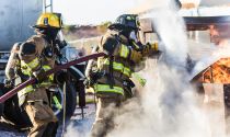 Firefighters work together in a training exercise to put out a fire