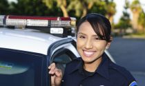 A female police officer stands by her patrol car