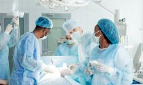 A surgical technologist assists a doctor with a patient in an operating room