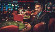 Male casino manager in a suit sits at a gaming table in a casino